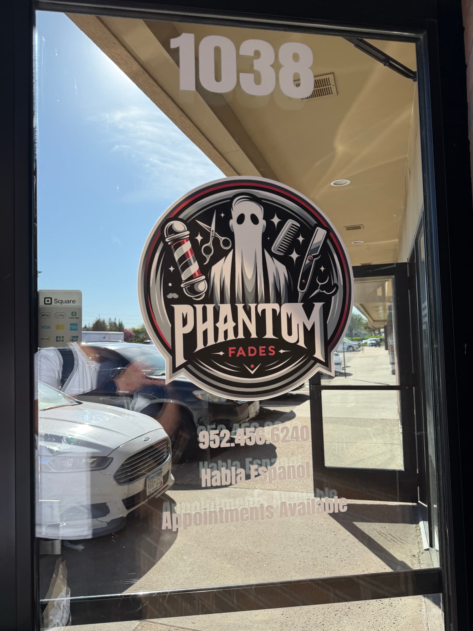 Phantom Fades storefront window with the phantom shield logo and address