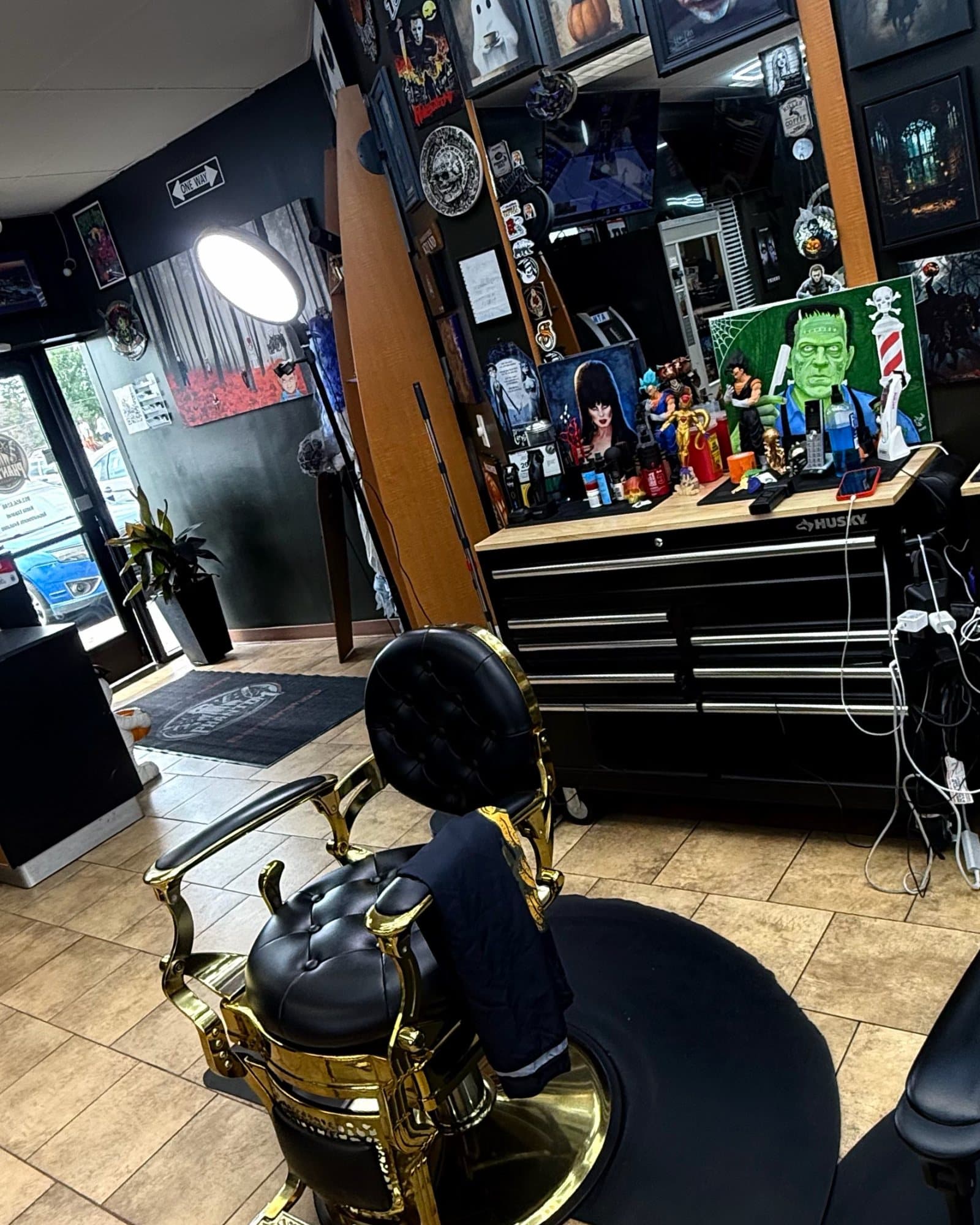 Antique gold barber chair at a Phantom Fades station, with Scream, Joker, and Frankenstein art on the wall behind it